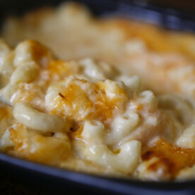 Close-up of Creamy Smoked Mac and Cheese with Three Cheeses, featuring a golden, melted cheese topping and a spoon scooping up the rich, smoky sauce.