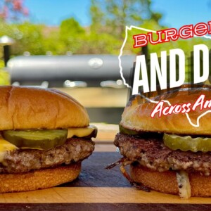 Two cheeseburgers with pickles sit on a wooden board outdoors, a grill in the background. Text overlays the image: Burgers and Dogs Across America in bold white and red letters, featuring an Oklahoma fried onion burger.