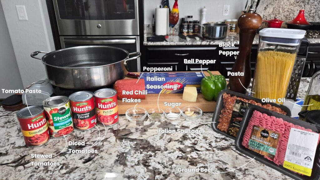 Kitchen counter ready for southern spaghetti with labeled ingredients: tomato paste, stewed tomatoes, diced tomatoes, red chili flakes, Italian seasoning, pepperoni, bell pepper, Italian sausage, ground beef, black pepper, pasta, sugar, and olive oil.