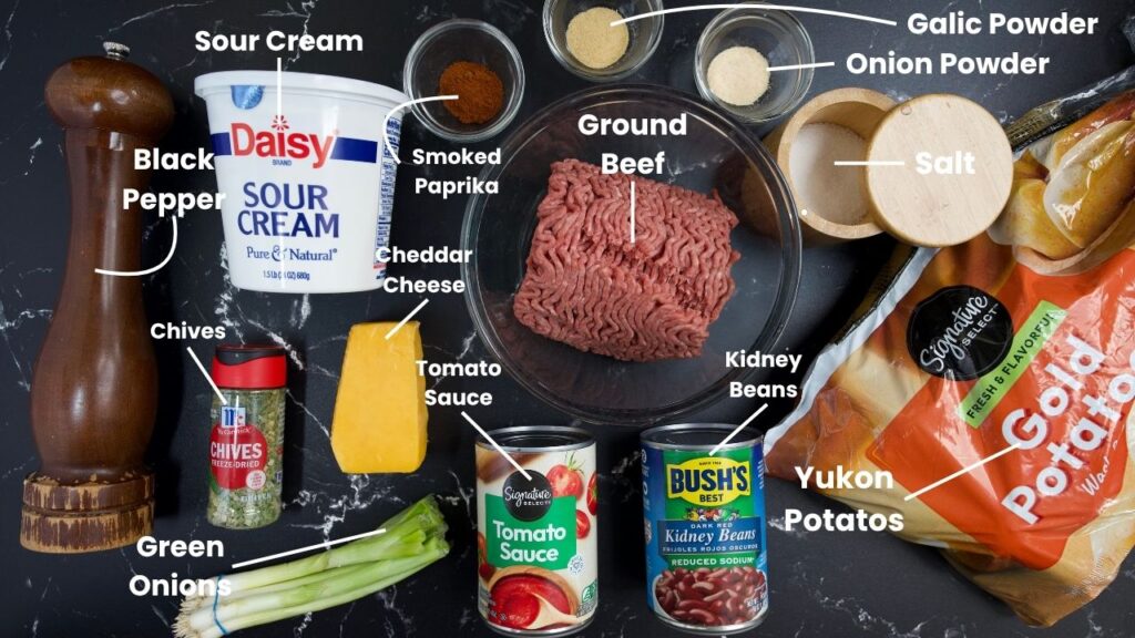 Ingredients for Crockpot Ground Beef Potato Casserole are laid out, including ground beef, Yukon potatoes, sour cream, cheddar cheese, kidney beans, tomato sauce, spices, black pepper, chives, and green onions.