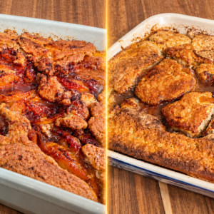 Two rectangular baking dishes on a wooden table, each containing a golden brown, bubbly peach cobbler with visible baked peaches and a rustic, biscuit-like topping.