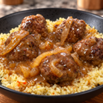 A black bowl filled with yellow rice topped with five meatballs in brown onion gravy, placed on a wooden surface.