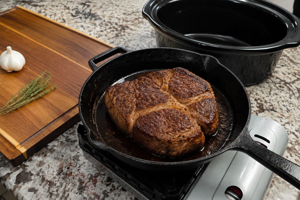 Chuck roast browning in a cast-iron skillet before slow cooking