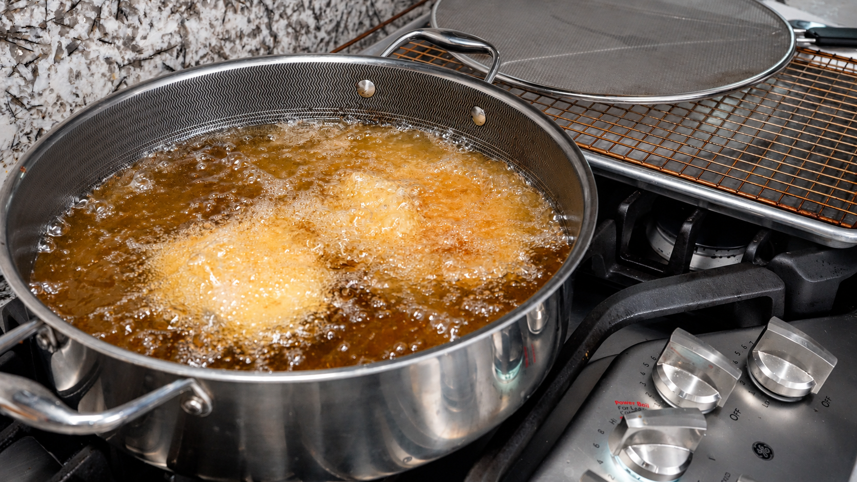 Breaded chicken frying in bubbling oil in a deep skillet
