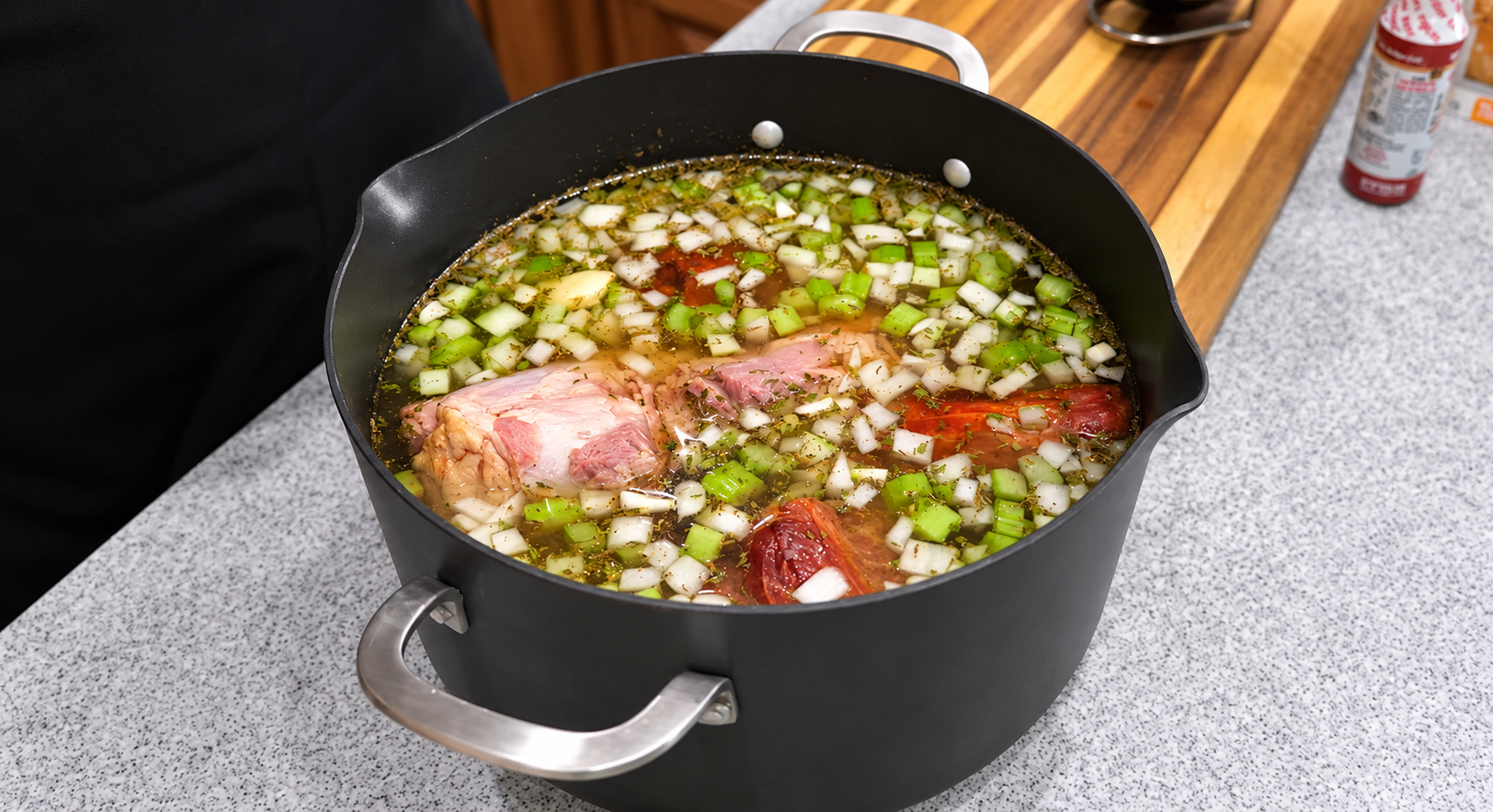 Ham bone and ham shank covered with broth, vegetables, and herbs.