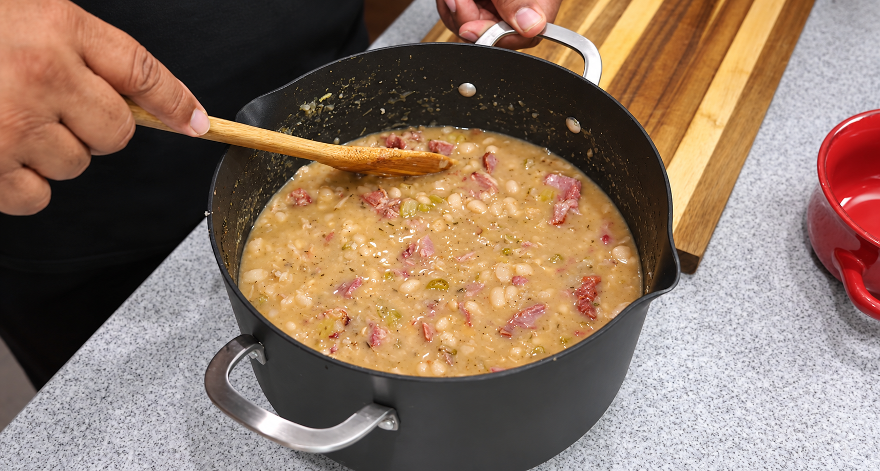Finished creamy white bean soup with ham being gently stirred.