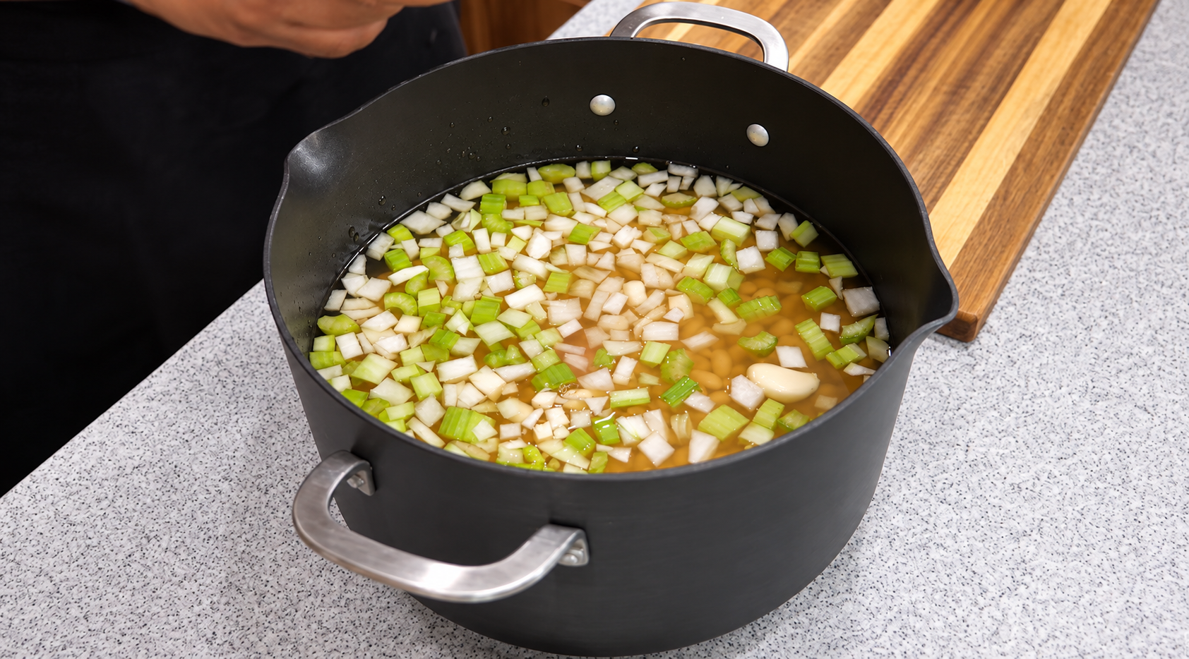 Chicken broth and smashed garlic added to the beans, onion, and celery.