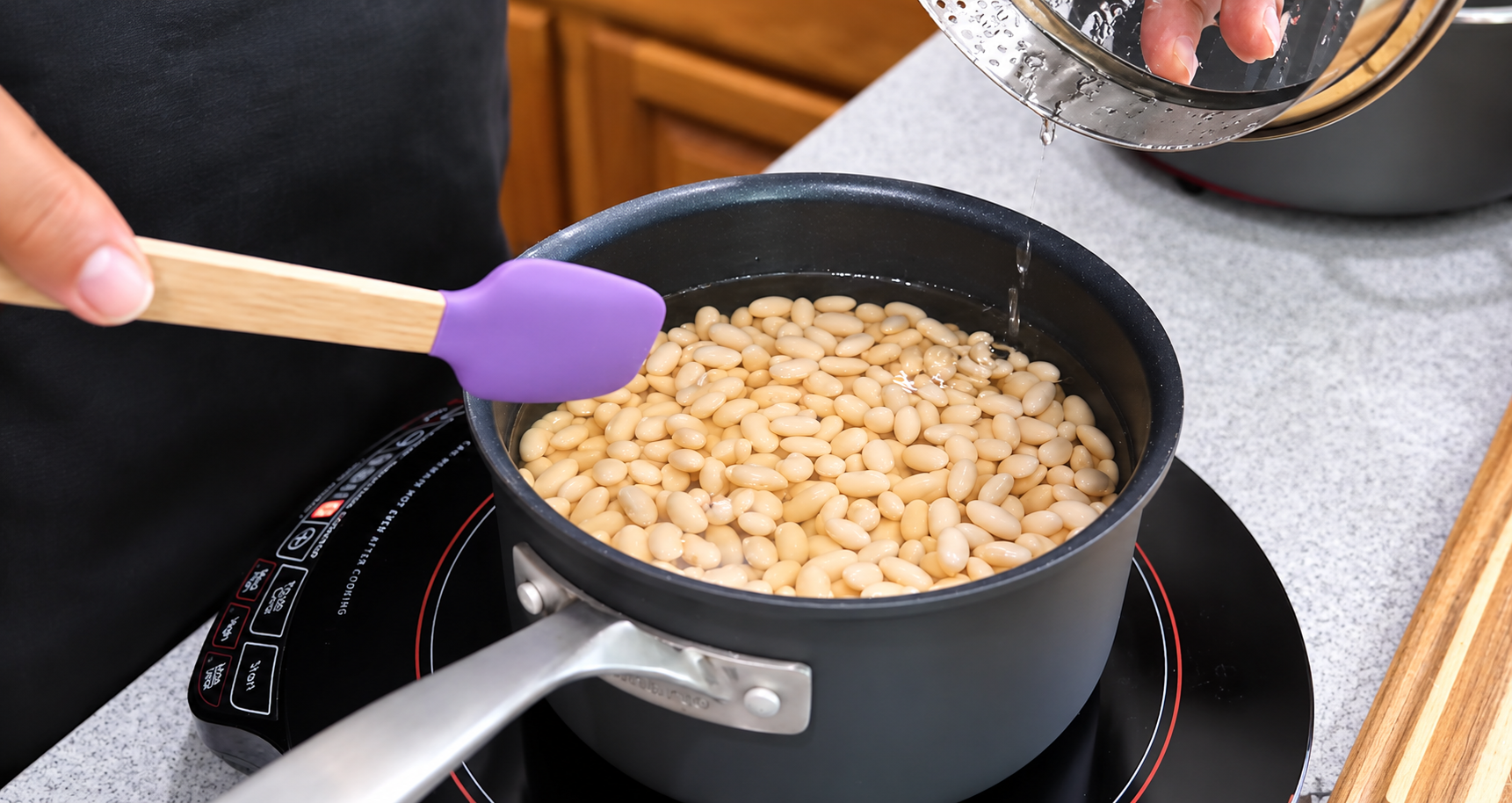 White beans soaking in water in a saucepan with the lid lifted.
