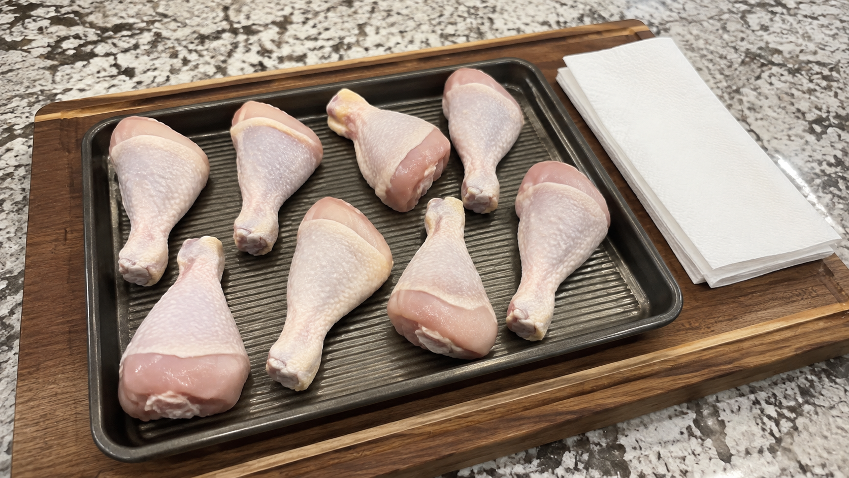 Raw chicken drumsticks patted dry on a baking sheet for hot honey ranch chicken legs.