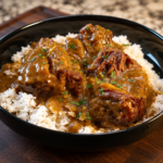 A black bowl filled with white rice topped with beef in a brown gravy, garnished with fresh herbs.